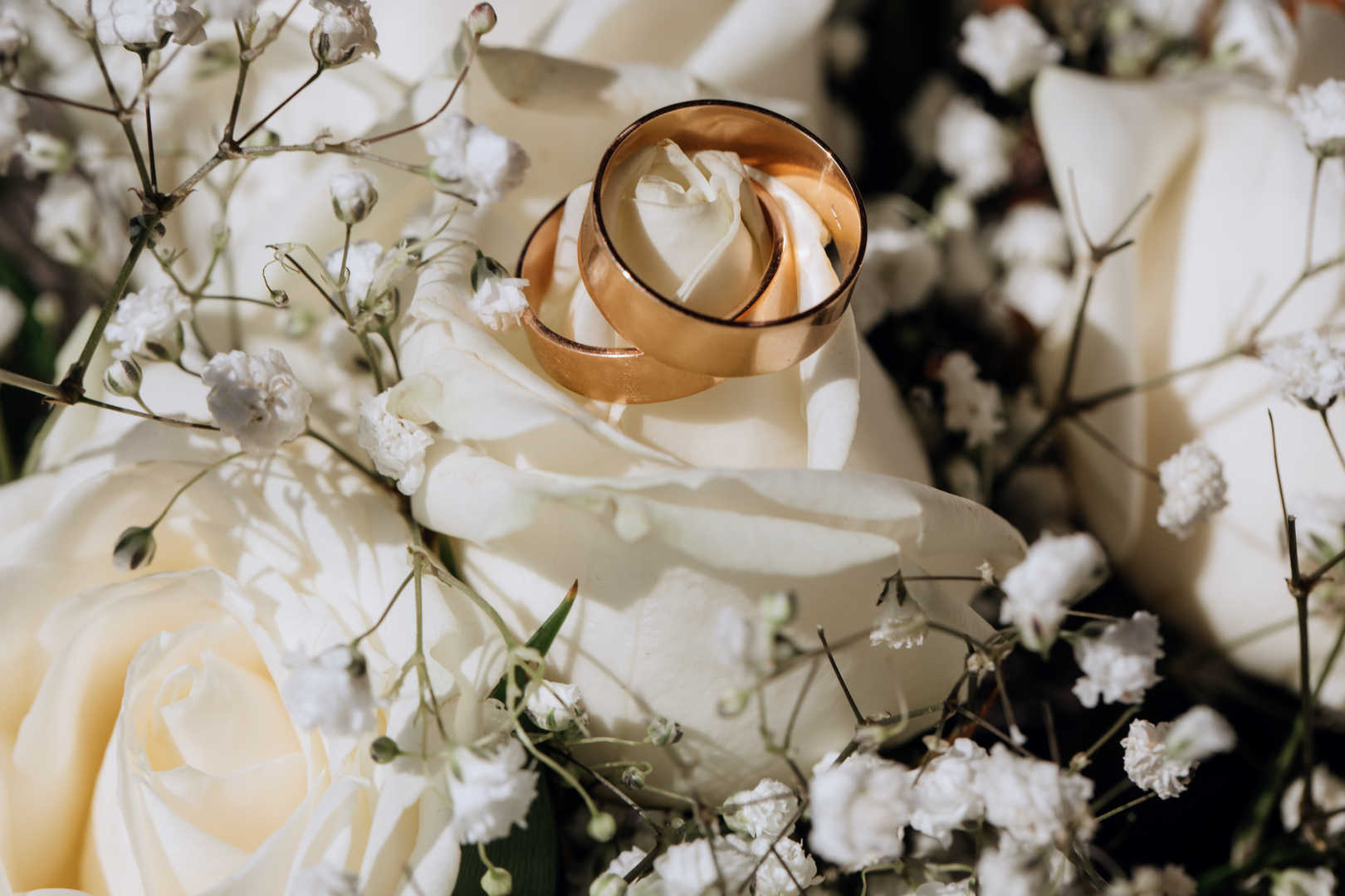 Anneaux de mariage en or sur la rose blanche du bouquet de mariage tout organisé par un wedding planner haut de gamme.